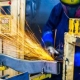 Factory worker using a grinding machine with bright sparks flying, wearing protective gear
