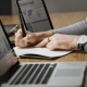 Person analyzing company growth data on laptop and writing notes in a notebook