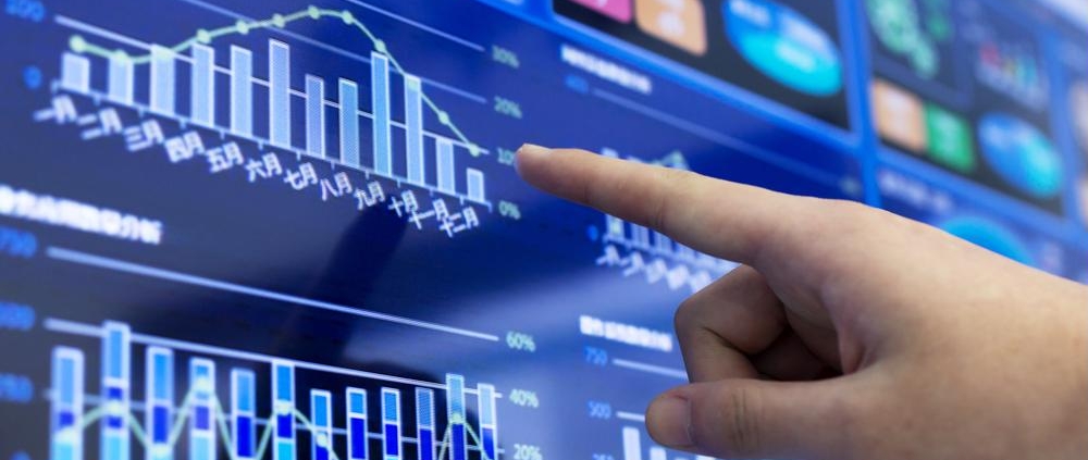 Hand pointing at digital dashboard with bar charts and graphs for data analysis